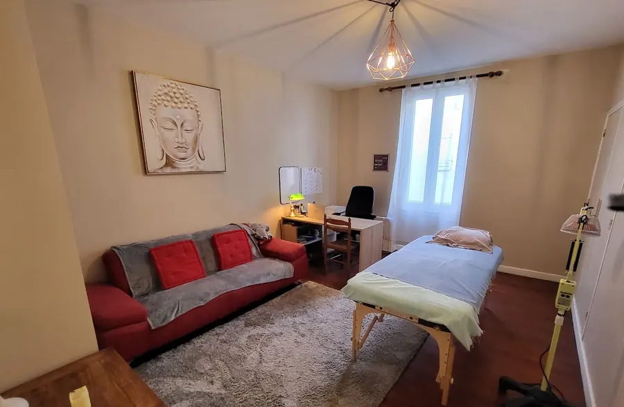 La salle de soin du cabinet Zenergy : table de soin, canapé, parquet ancien et lampe chauffante